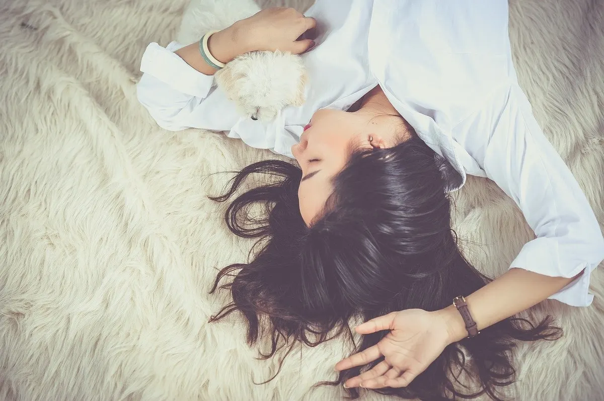 A woman lying on a soft rug, relaxed with her eyes closed