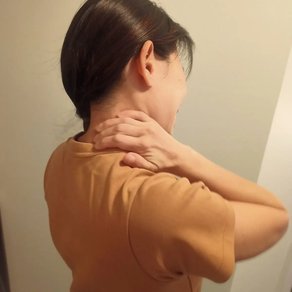 A woman holding the back of her stiff neck