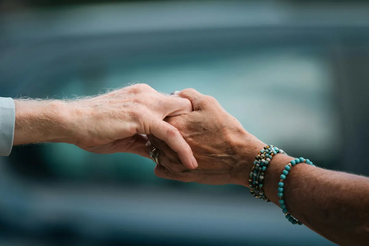 A carer gently holding an older person's hands